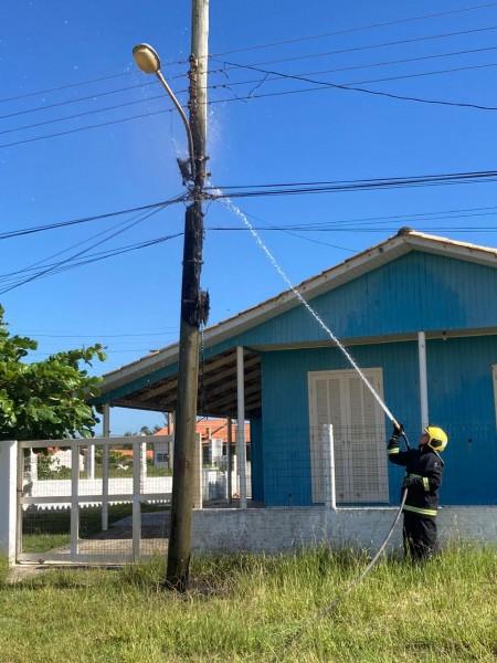 Bombeiros combatem fogo em poste de madeira