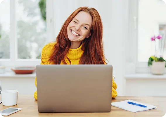 Mulher sorrindo usando o notebook em casa